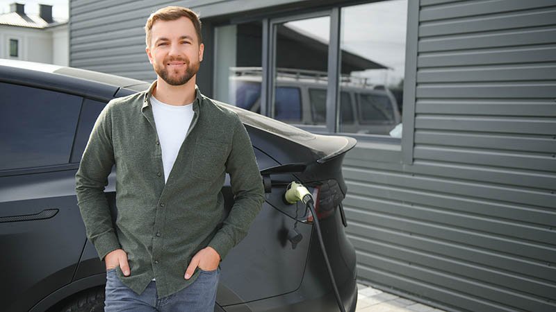 Fornøyd mann lader elektrisk firmabil.