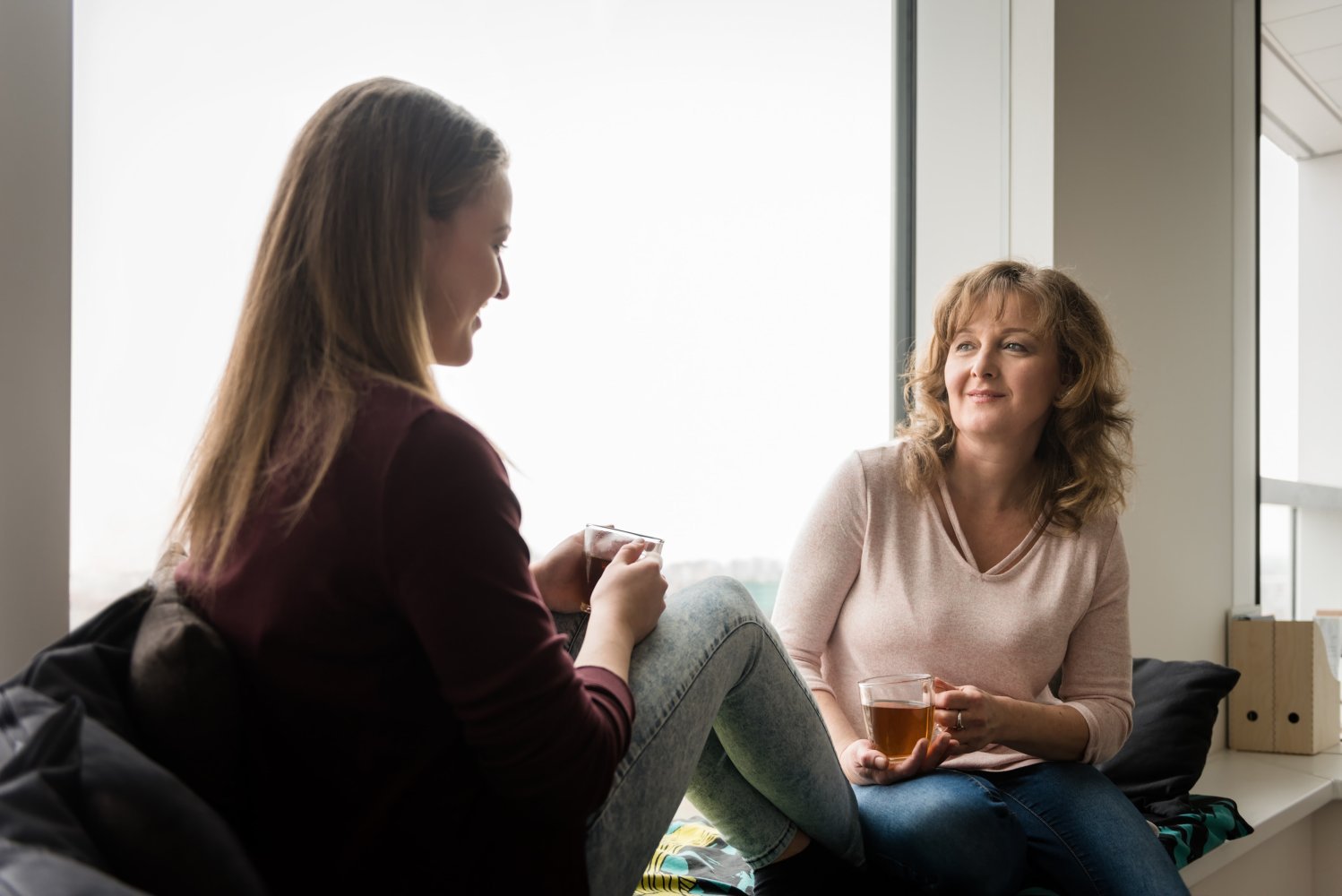 Bildet viser en mor og en datter som sitter og snakker sammen, med en kopp te. 