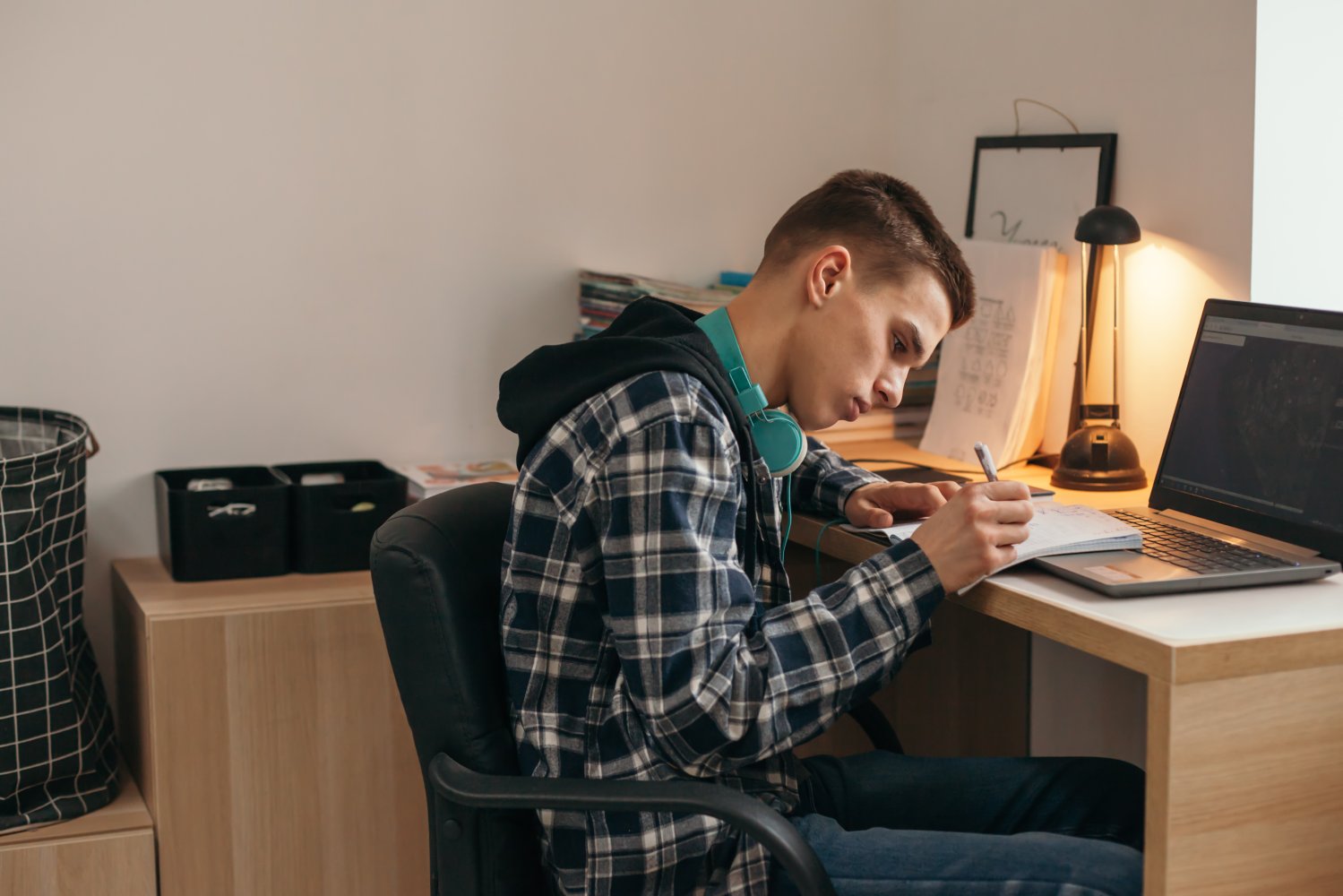 Bildet viser en ung gutt som sitter hjemme og jobber med skole