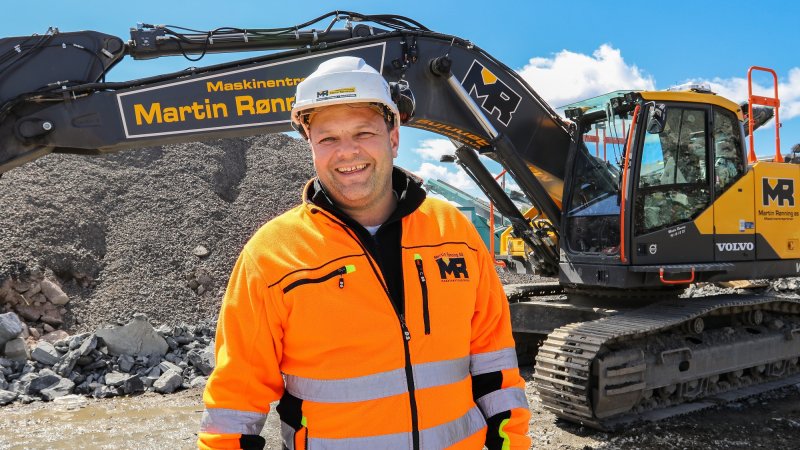 Svein-Erik Ryen står foran en gravemaskin og smiler.